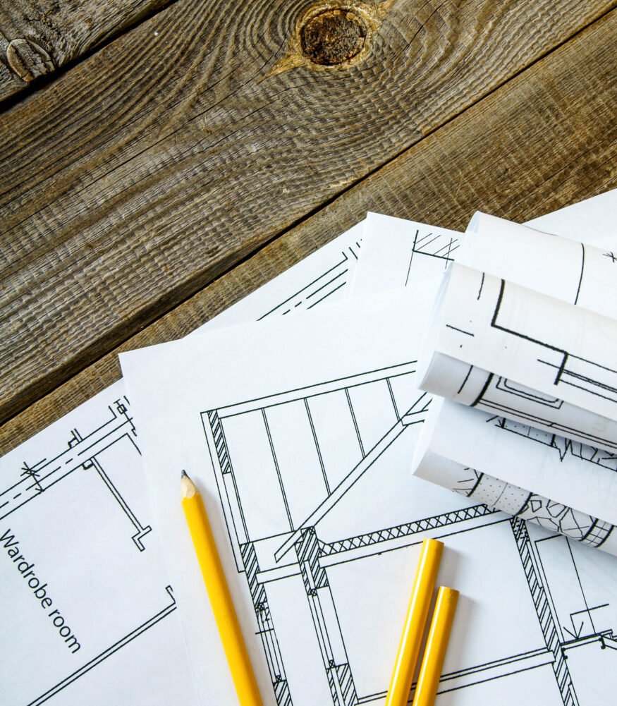 We build a building. House construction. Many drawings for building and pencils on old wooden background.